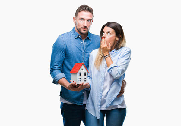 Young couple in love holding small house with shame for mistake