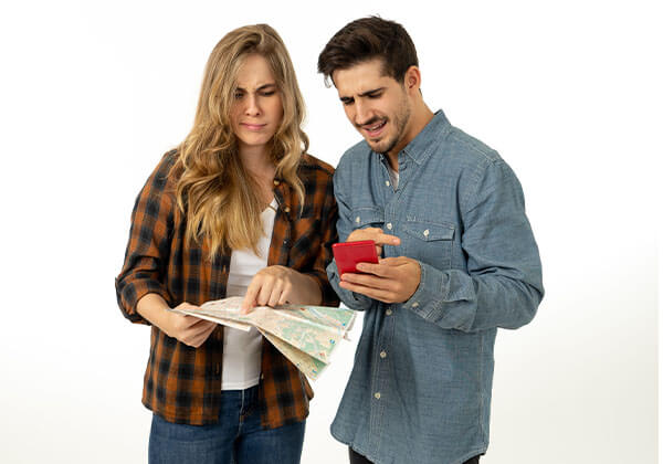 Young couple consulting a map and smart phone gps looking confused